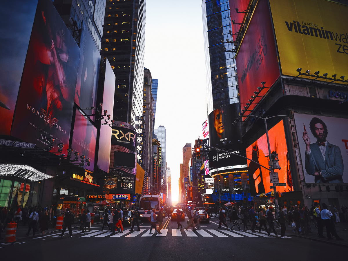 Crowds and illuminated billboards in Times Square at sunset