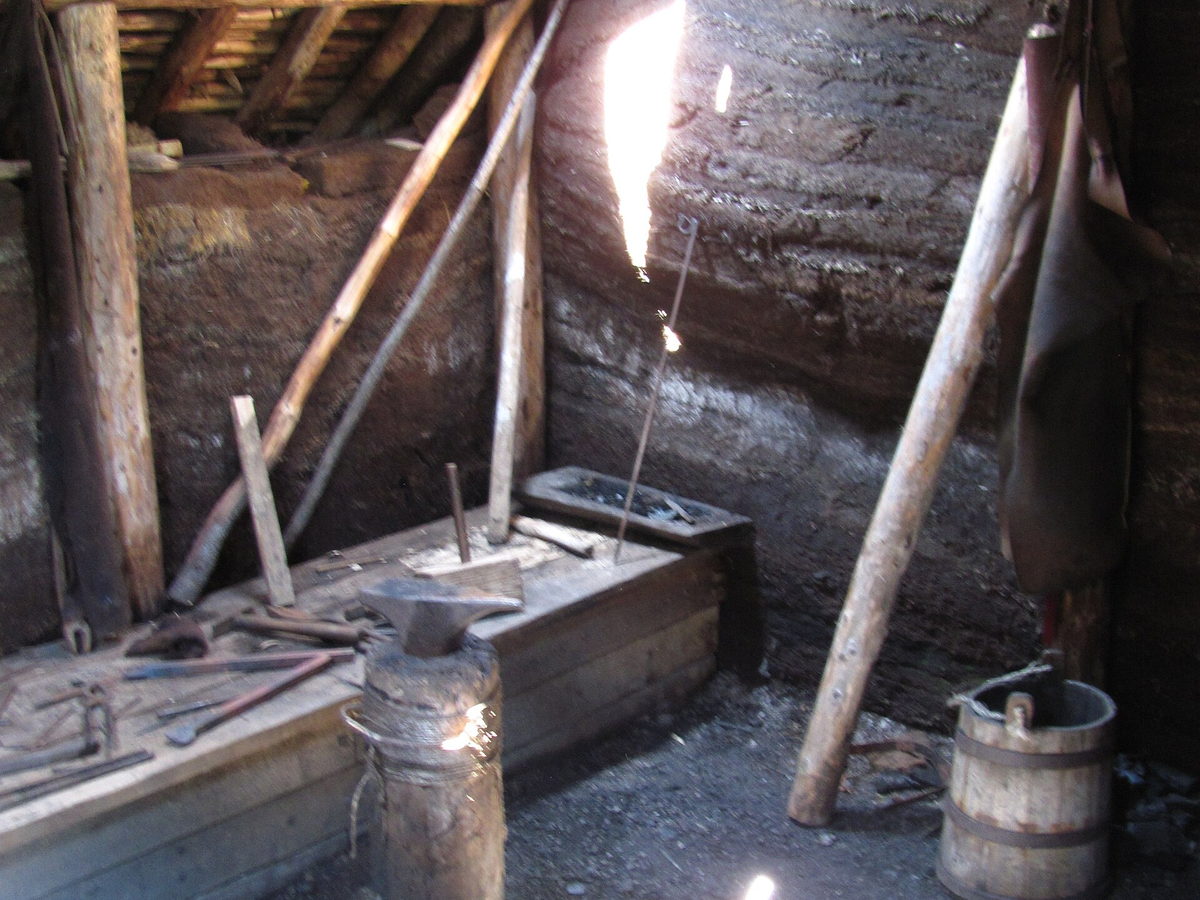 Interior of a reconstructed Norse building at L'Anse aux Meadows with a wooden workbench and tools
