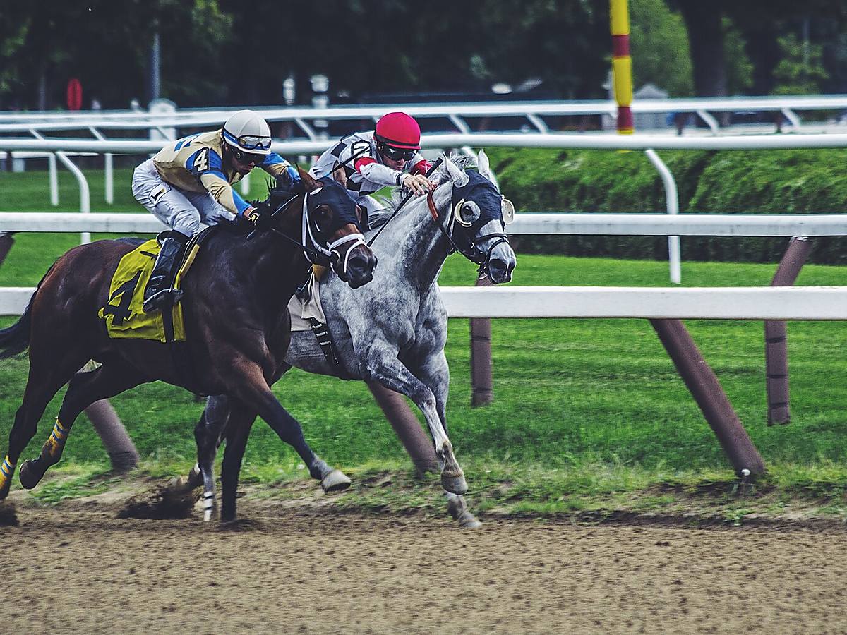 Two jockeys riding horses head-to-head in a close race