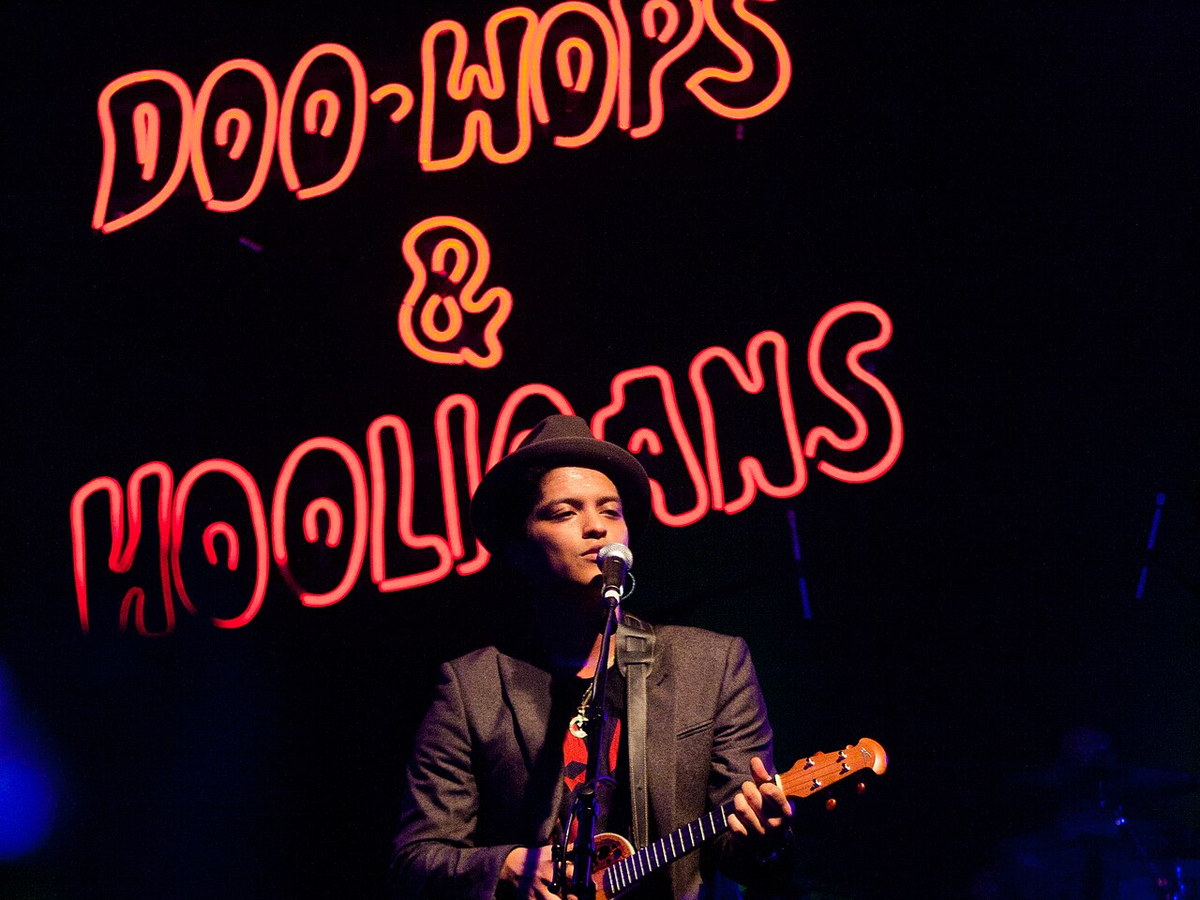 Bruno Mars performing in concert with a guitar