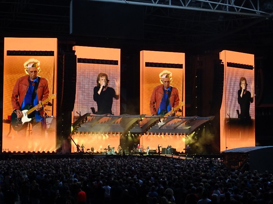 The Rolling Stones performing live on a brightly lit concert stage
