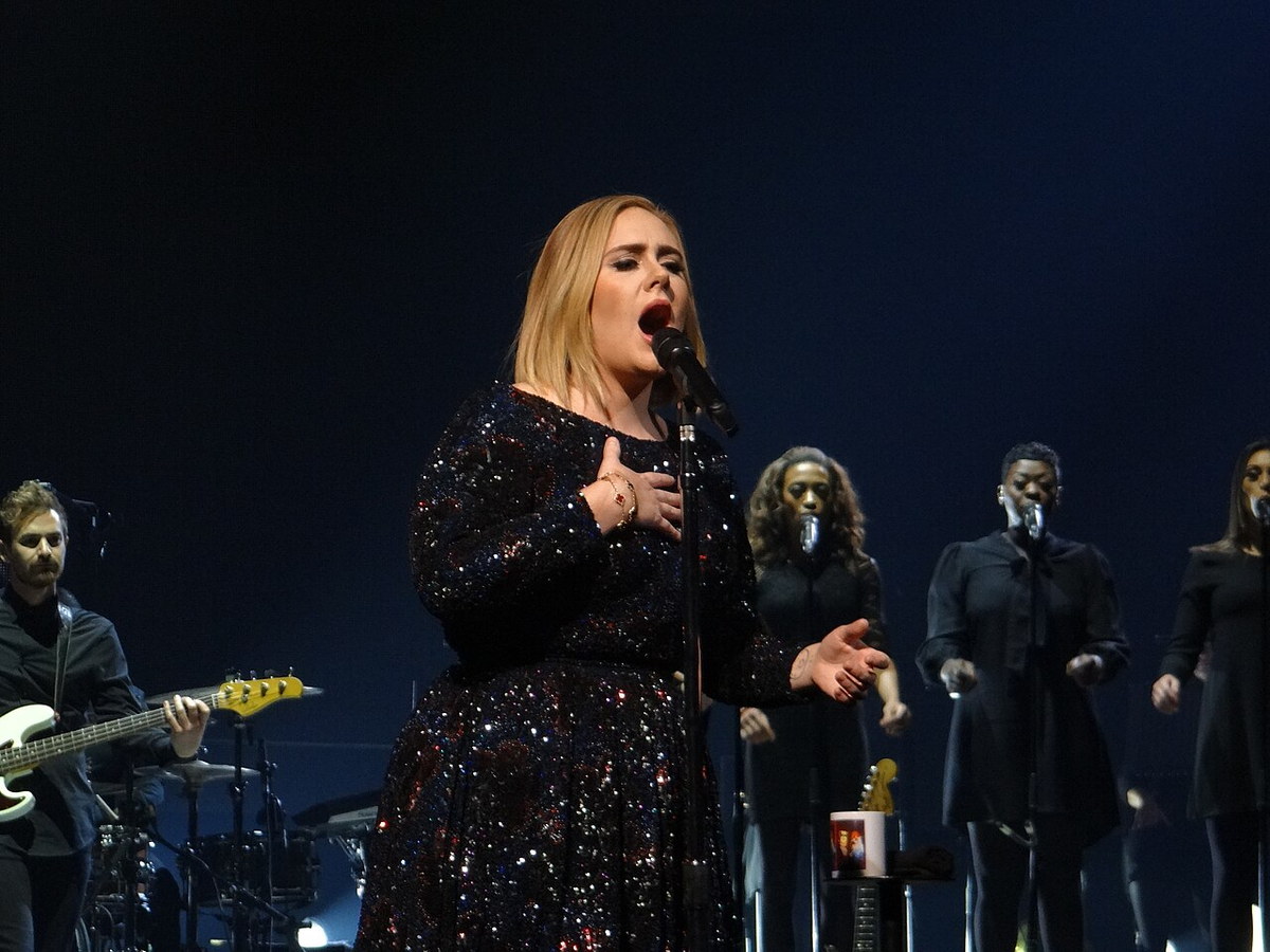 Adele performing under stage lights during her 2016 tour