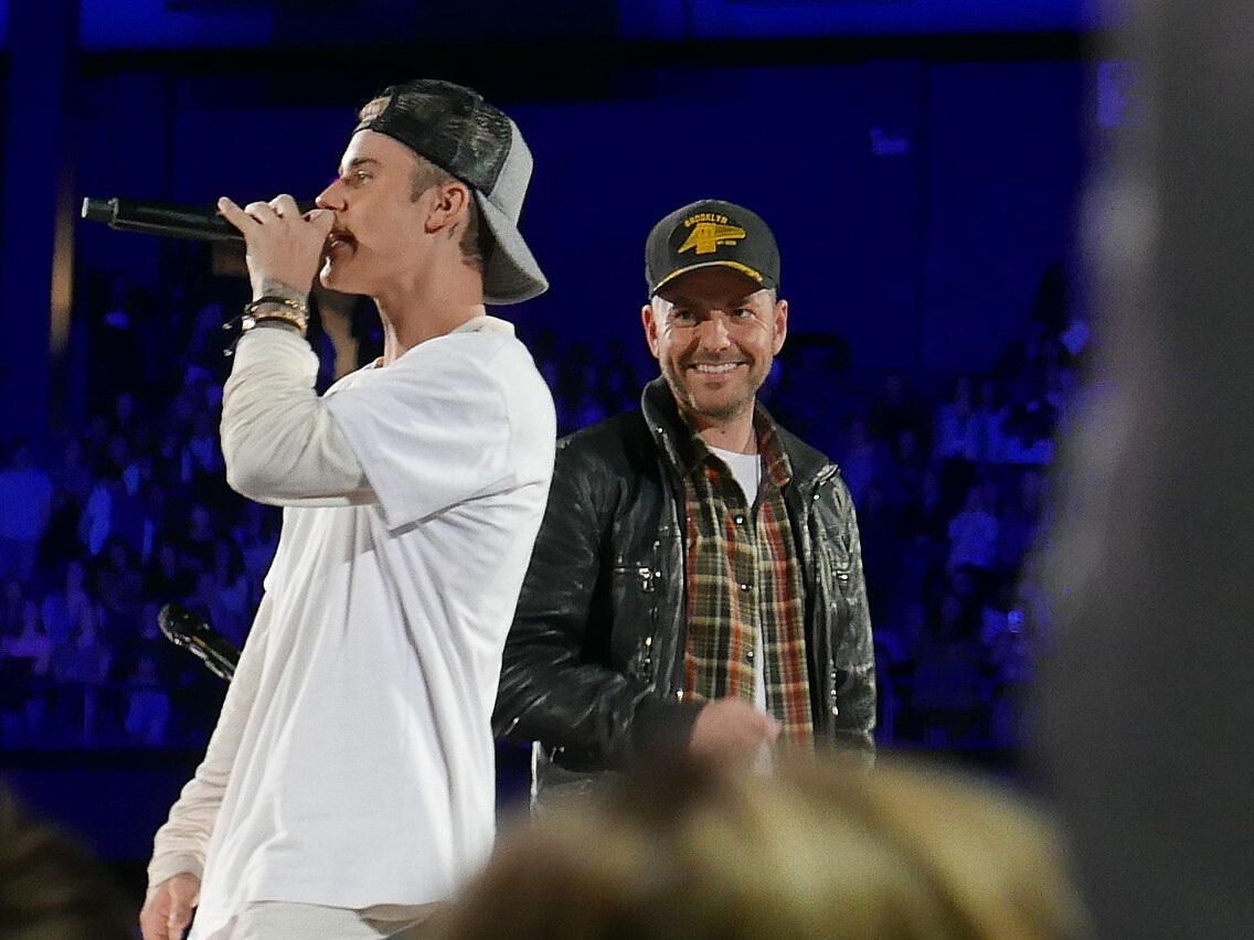 Justin Bieber singing into a microphone with Scooter Braun beside him