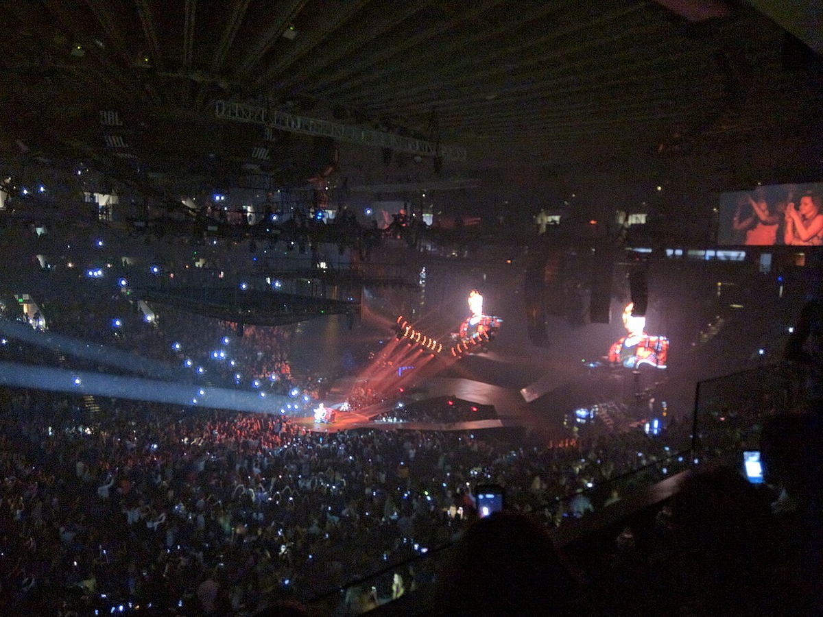 Justin Bieber performing on a brightly lit stage in a large arena