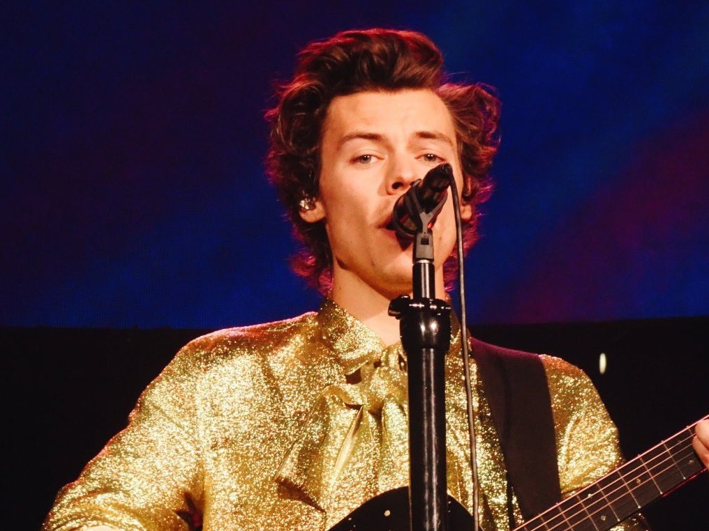 Harry Styles singing and playing guitar during his 2018 tour in Denver