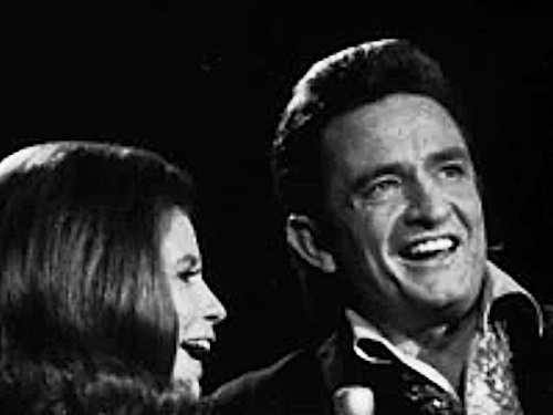 Johnny Cash standing beside June Carter during their music career