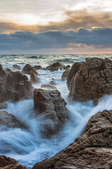 Ocean waves breaking against rocks at sunset in La Corniche, France