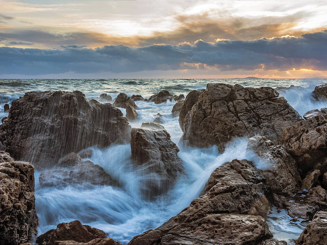 Ocean waves breaking against rocks at sunset in La Corniche, France