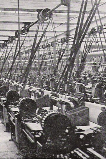 Rows of belt-driven weaving machinery inside a historic Lancashire cotton mill