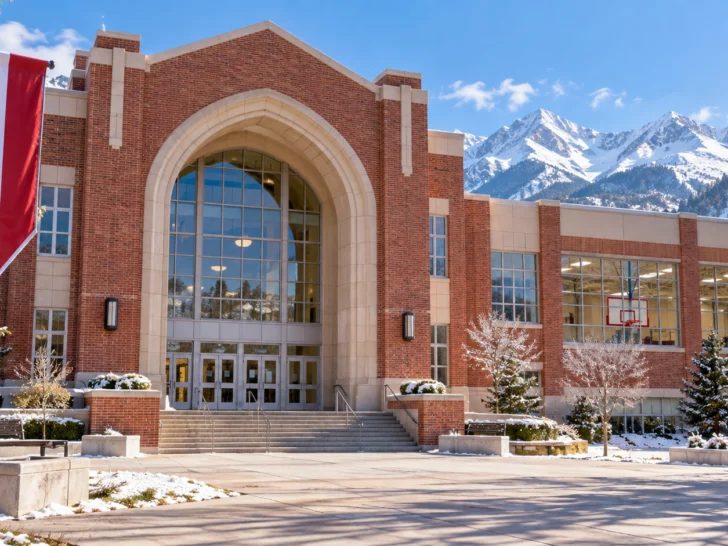 Red-brick high school and gym at the foot of snowy mountains