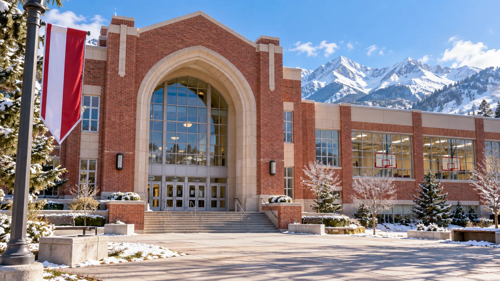 Red-brick high school and gym at the foot of snowy mountains