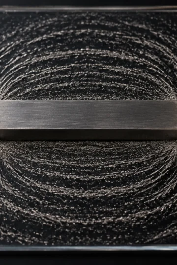 Iron filings tracing curved field lines around a bar magnet