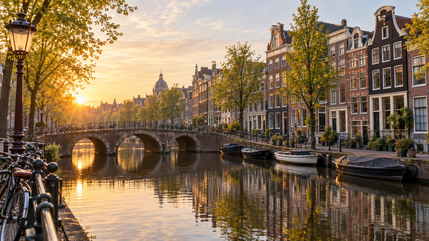Historic canal houses bicycles and an arched bridge in Amsterdam at sunrise