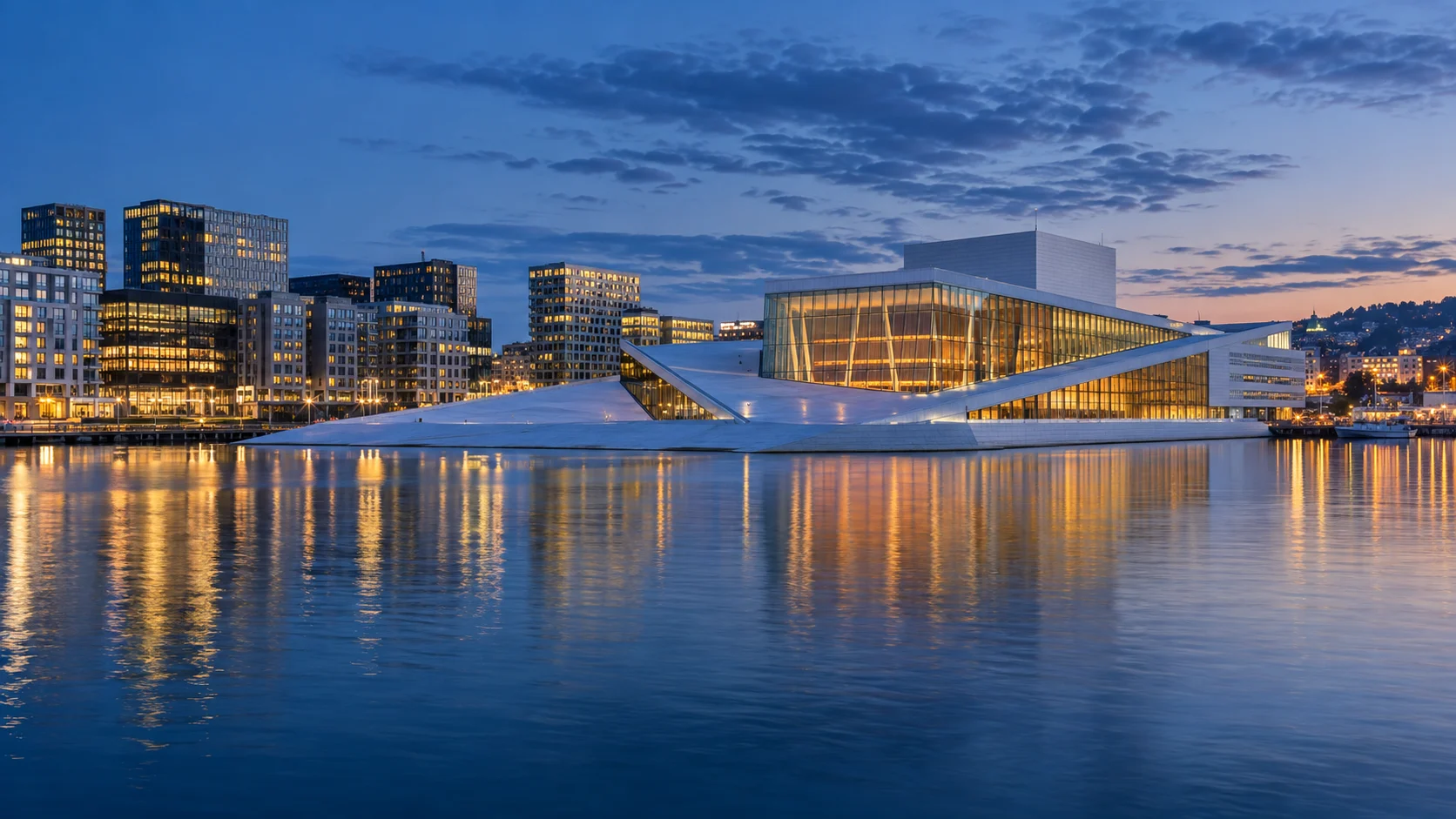 Oslo Opera House glowing beside the calm harbor at blue hour