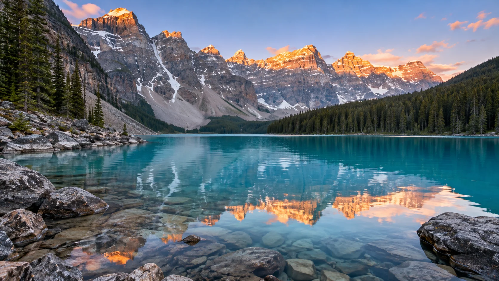 Sunrise colors the peaks above turquoise Moraine Lake in Alberta.