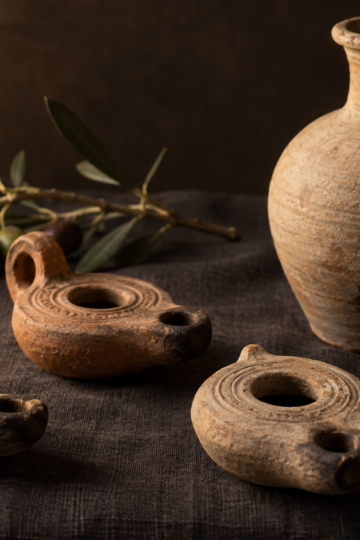 Ancient clay oil lamps sit beside an olive-oil jug.
