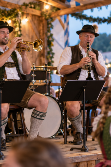 A Bavarian brass ensemble performs on a wooden festival stage.