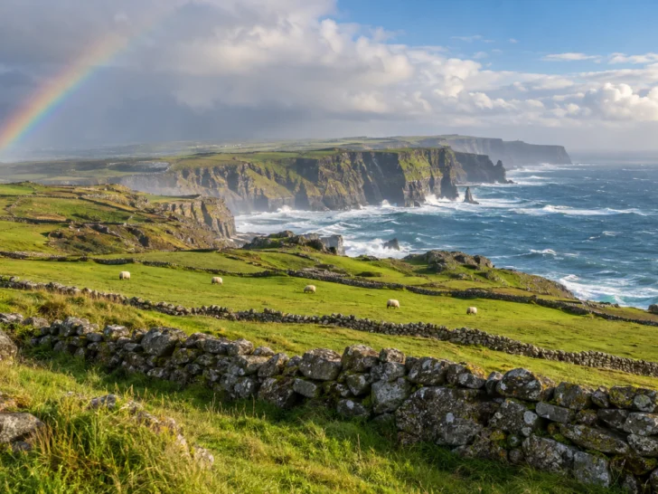 Rainbow over green Irish pastures and windswept Atlantic sea cliffs