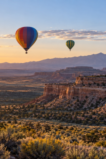 Colorful hot-air balloons floating above New Mexico mesas at sunrise