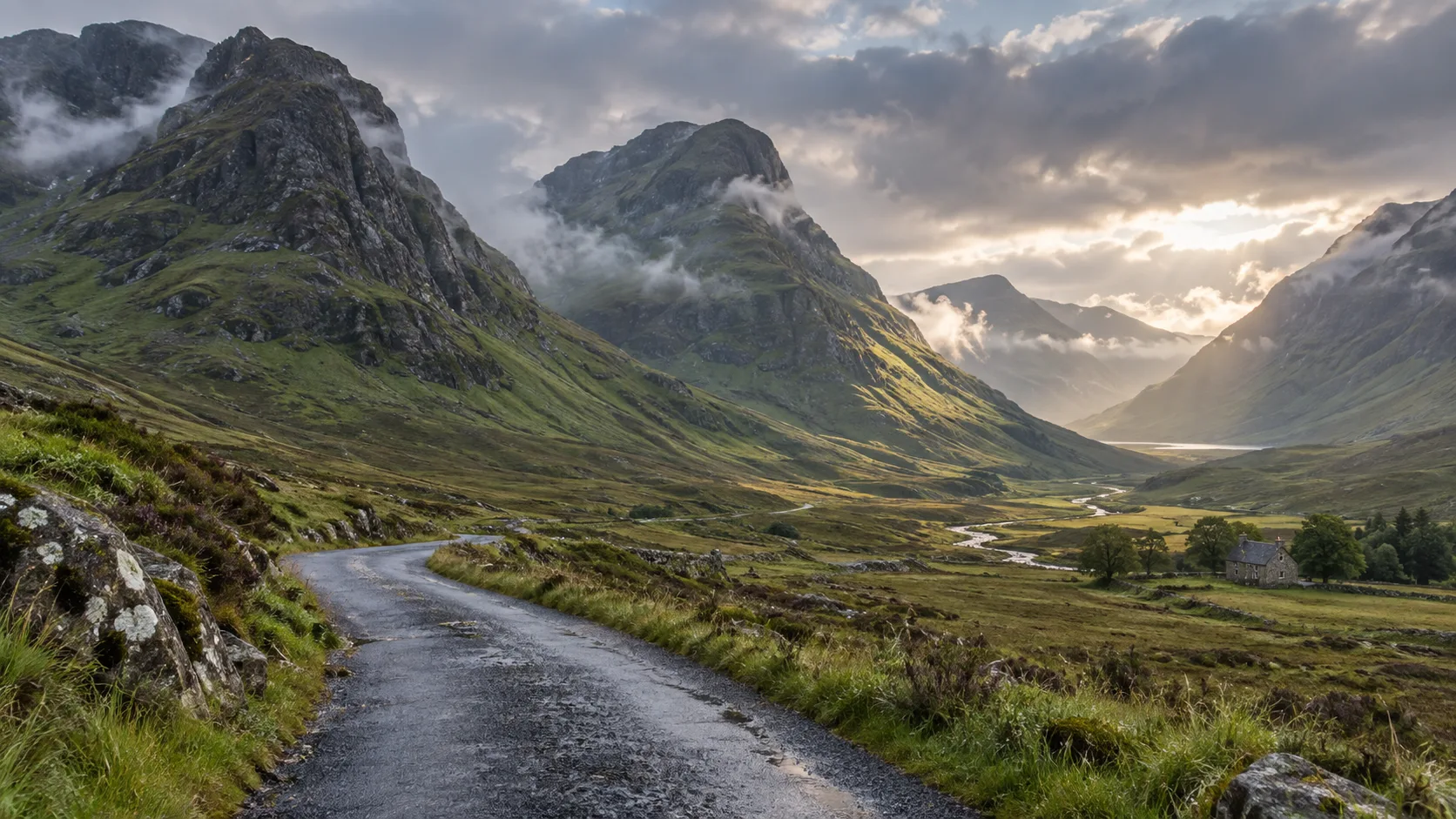 Misty green mountains and winding road through Glen Coe in Scotland